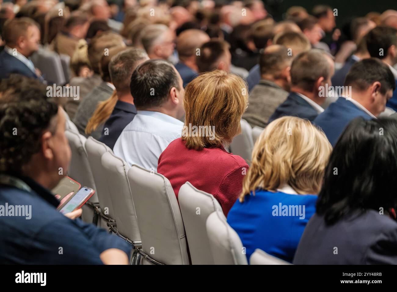 Le persone sedute a una conferenza, ascoltando attentamente gli oratori e le presentazioni. Foto Stock