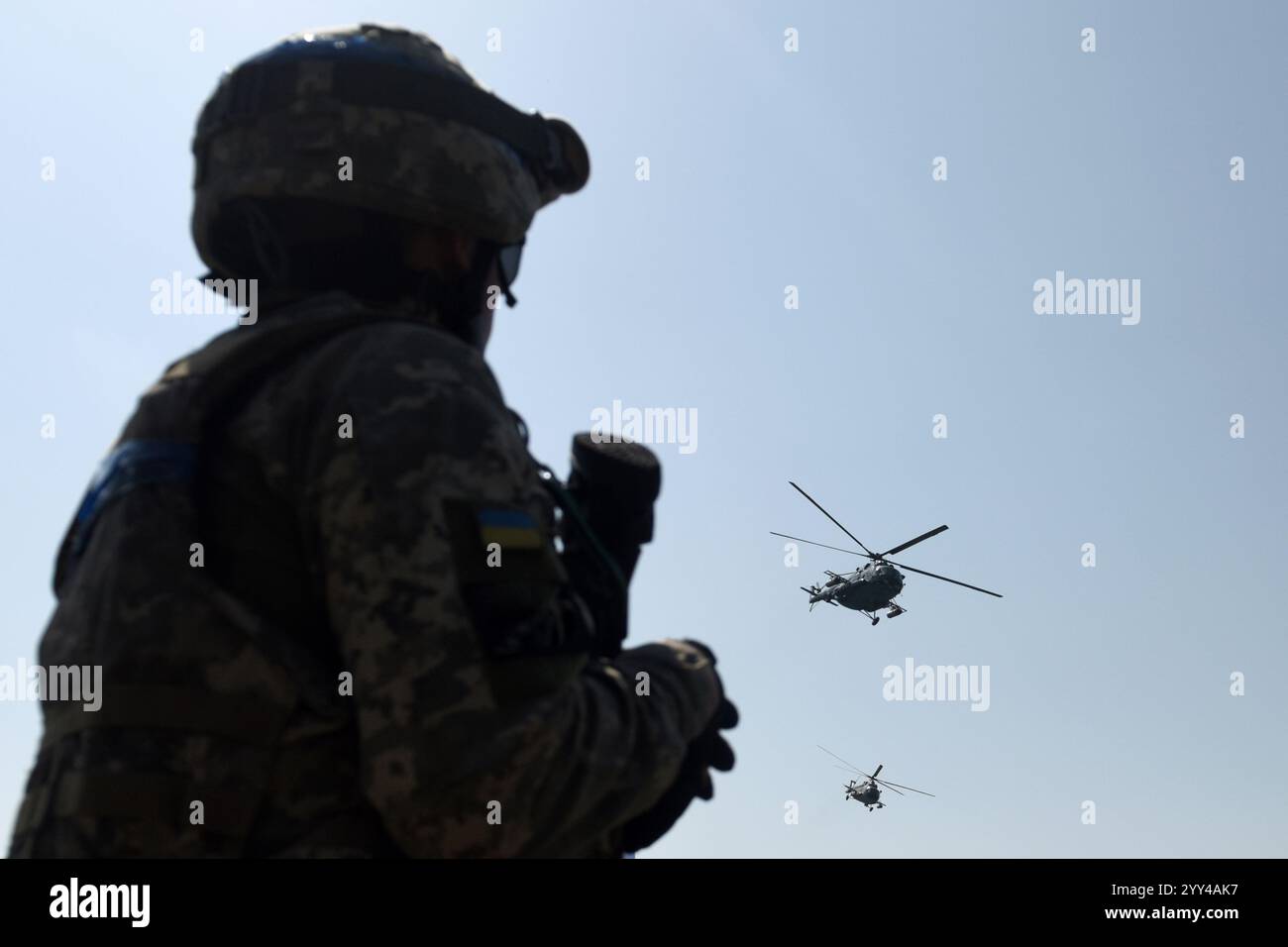 Soldato ucraino guarda gli elicotteri militari che volano nel cielo. Guerra in Ucraina Foto Stock