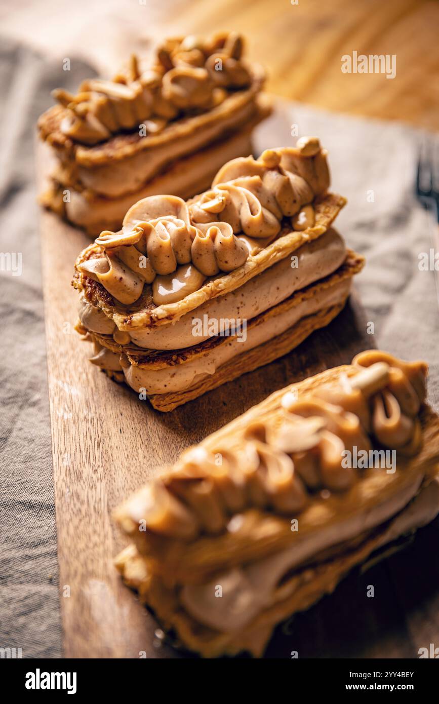 Tre millesimi di pasta di feuille rettangolari conditi con crema al burro di arachidi e arachidi tritate sono posti su un tavolo da portata in legno Foto Stock