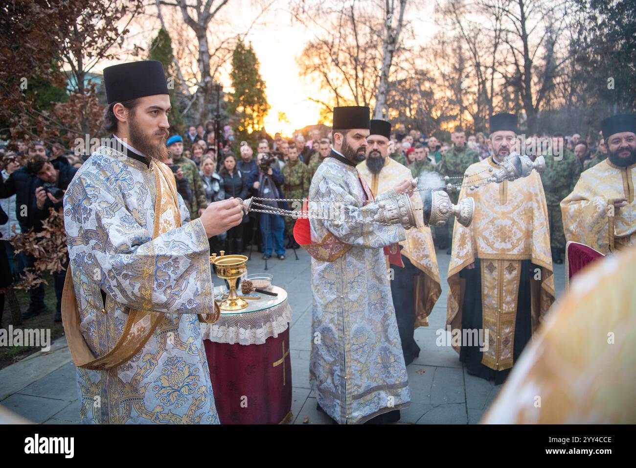 I sacerdoti serbi tengono la cerimonia prima di bruciare i rami di quercia essiccati - il simbolo di Yule per la ChristmasEve ortodossa di fronte alla chiesa di Santa Sava Foto Stock