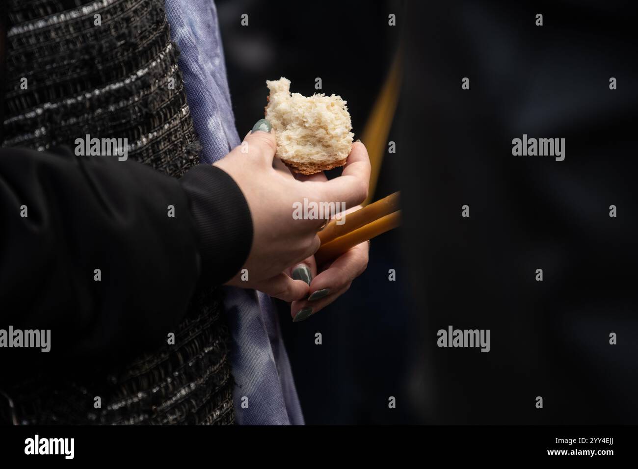 Adulta e fedele in Gesù Cristo donna in Santa comunione pregate e tenendo pane e candele. Santa comunione in chiesa. Foto Stock