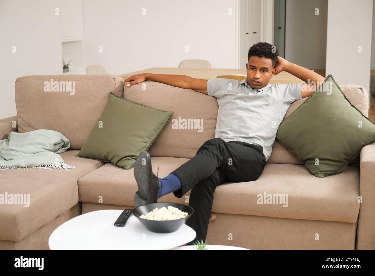 Un giovane afroamericano gode di un momento di relax a casa. La scena riflette il tempo libero, il comfort e il calore, mettendo in risalto un ambiente di cupole moderne Foto Stock