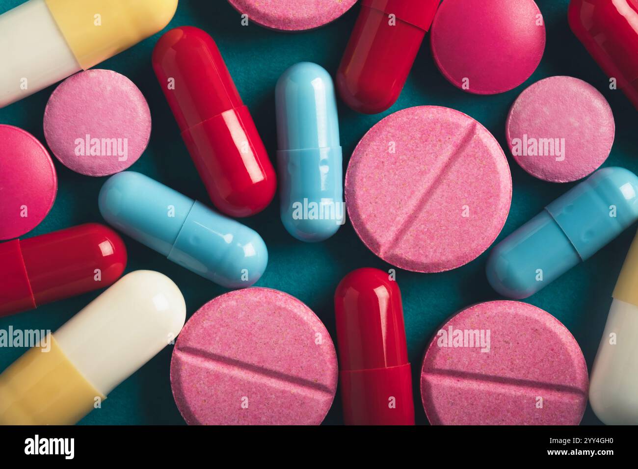 Una disposizione vibrante di varie pillole colorate e capsule visualizzate su uno sfondo color ottanio questa composizione enfatizza la diversità nella forma e nel co Foto Stock