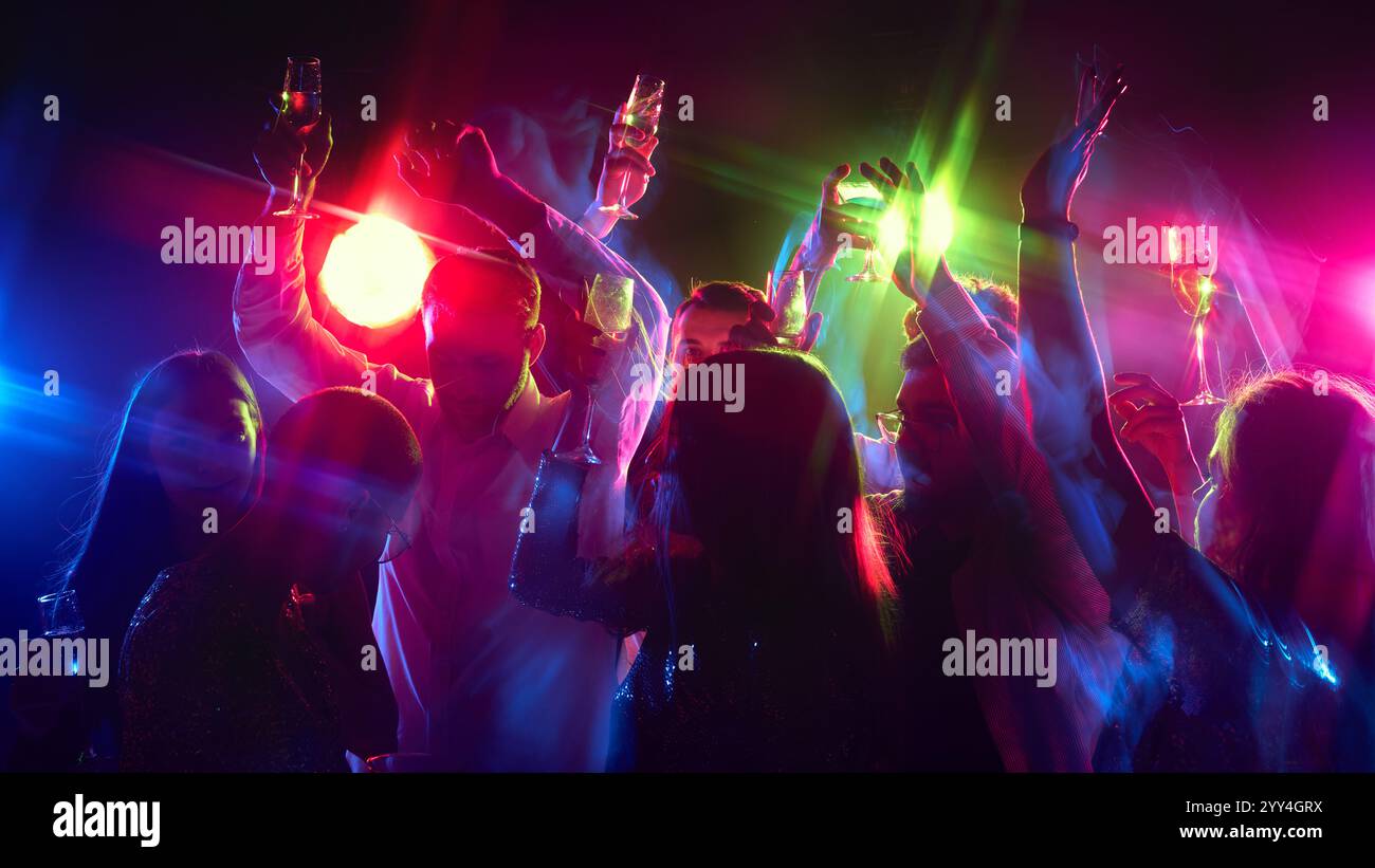 Le mani ondeggiano al ritmo, gli occhiali si aggrappano mentre la folla celebra la vita, la musica e condivide la felicità sotto le luci al neon. Foto Stock