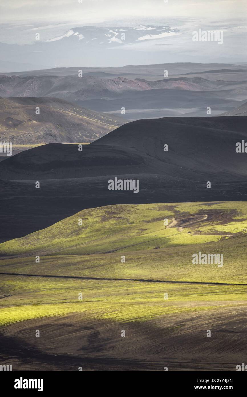 Una vista mozzafiato del vasto paesaggio islandese caratterizzato da colline vulcaniche ondulate e montagne lontane, che mostrano la splendida bellezza naturale dell'isola Foto Stock