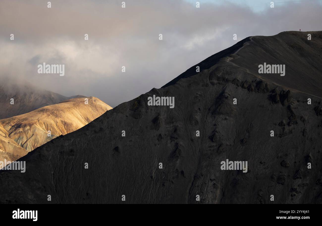 L'accattivante paesaggio montano islandese con ombre spettacolari e luce solare che si getta sulle aspre cime le nuvole di Moody aggiungono profondità a questo natu mozzafiato Foto Stock