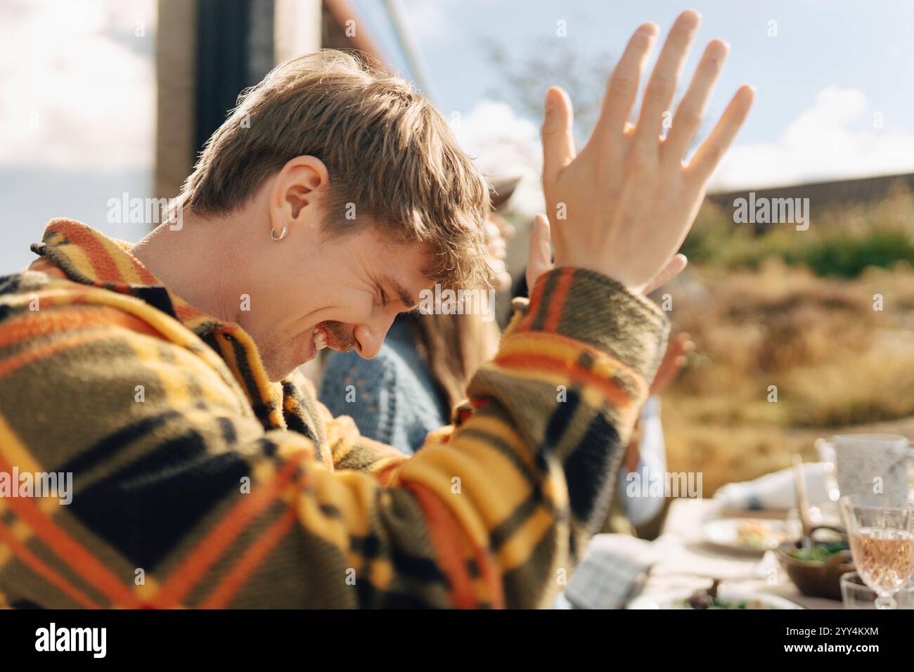 Giovane felice che si diverte ad una riunione sociale con gli amici nella giornata di sole Foto Stock