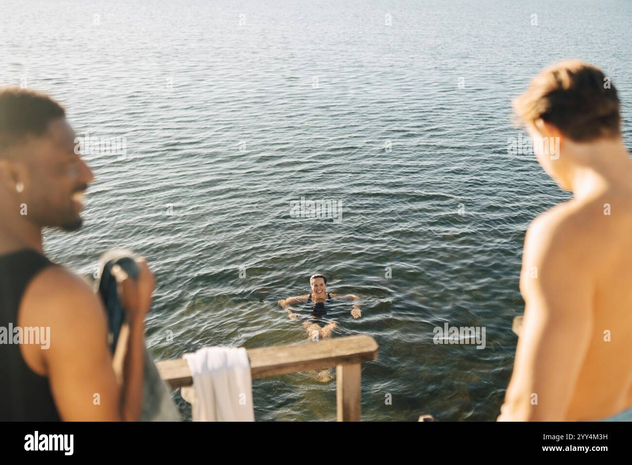 Vista ad alto angolo della donna sorridente che nuota in mare nelle giornate di sole Foto Stock