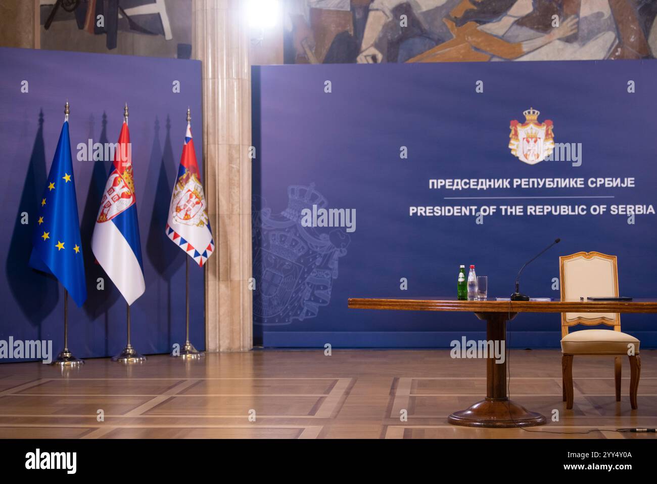 Parete blu con tubi metallici, tribuna con microfono e bandiere della repubblica di Serbia in conferenza stampa. Belgrado, Serbia Foto Stock