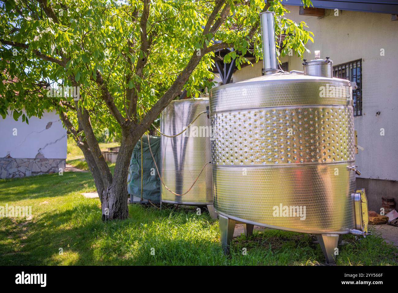 Grandi vasche metalliche per la fermentazione di vino e birra. Autocisterne o caldaie per la fermentazione del vino accanto alla casa di campagna. Fabbrica di vino. Foto Stock