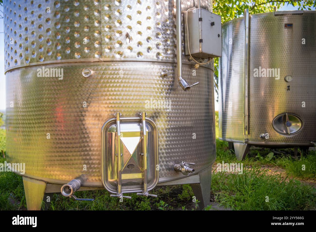Grandi vasche metalliche per la fermentazione di vino e birra. Autocisterne o caldaie per la fermentazione del vino accanto alla casa di campagna. Fabbrica di vino. Foto Stock