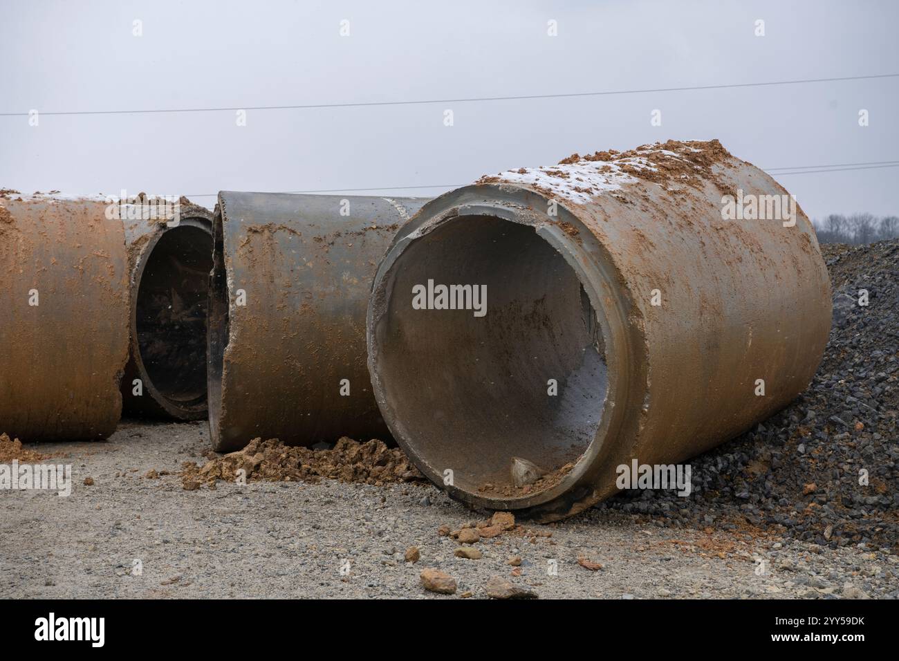 Pile di tubi di drenaggio in calcestruzzo impilato per pozzi e scarichi idrici, pronti per la costruzione. Background industriale. Foto Stock