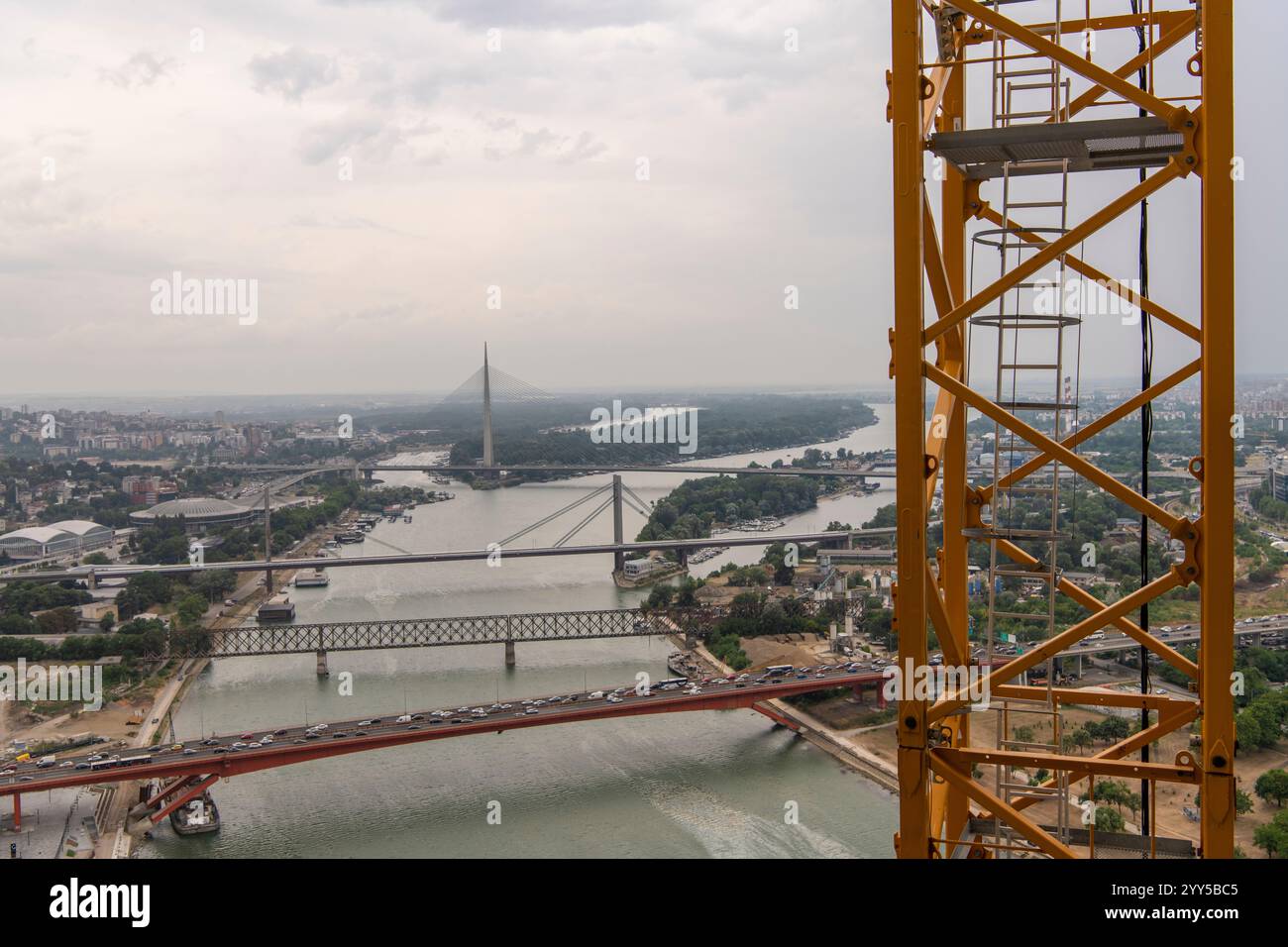 Vista ravvicinata della scala gialla di accesso alla gru, scala in acciaio. Cantiere di grattacielo a grattacielo. Splendido fiume panoramico, ponti e. Foto Stock