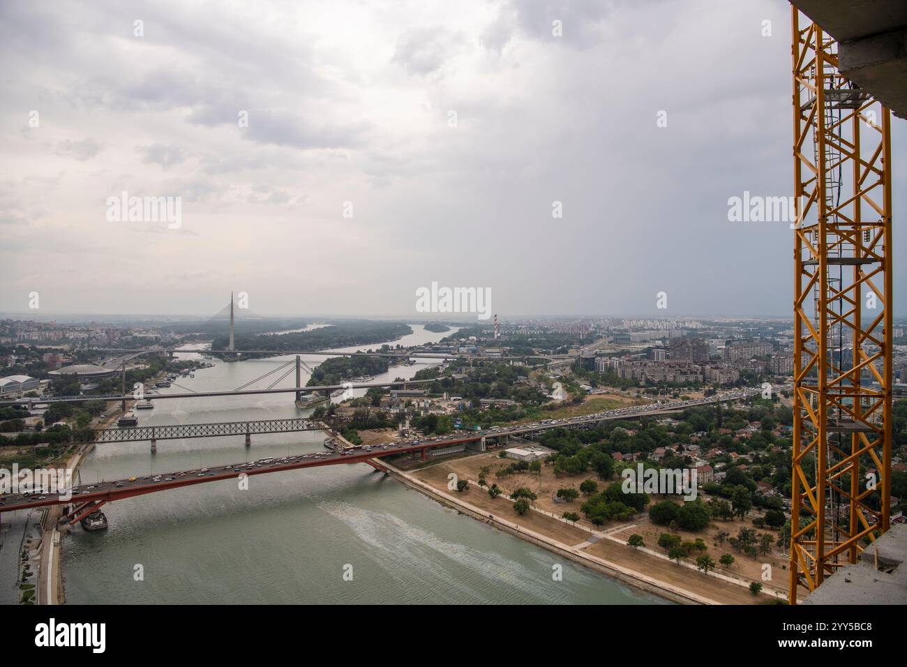 Vista ravvicinata della scala gialla di accesso alla gru, scala in acciaio. Cantiere di grattacielo a grattacielo. Splendido fiume panoramico, ponti e. Foto Stock