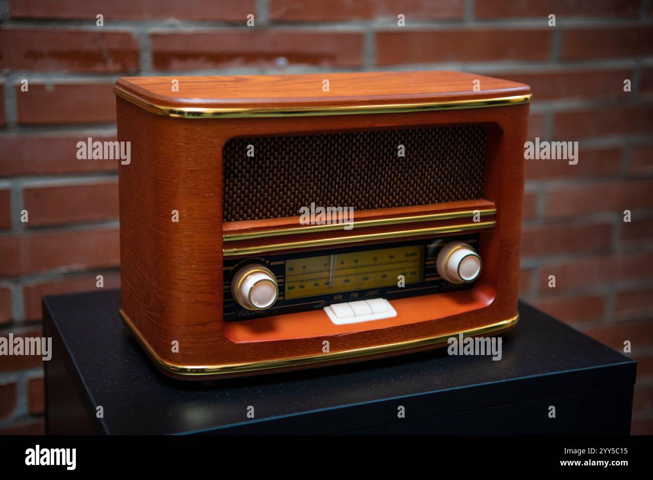 Ricevitore radiofonico in legno per trasmissioni retrò. Concetto di ascolto della musica. Vecchia radio d'epoca con mattoni rossi sullo sfondo. Il canale FM sta riproducendo musica. Foto Stock