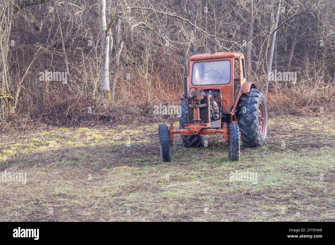 Il trattore. Vecchio rosso ruggine antico trattore da una fattoria nel bosco. Foto Stock