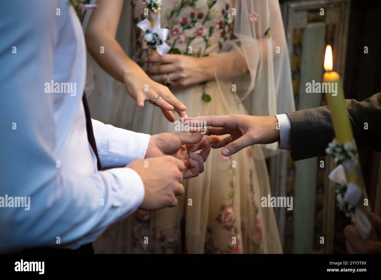 Una sposa e uno sposo che scambiano gli anelli di nozze in chiesa durante la cerimonia di nozze cristiana. Gli amanti si mettono gli anelli sulle dita. Primo piano Foto Stock