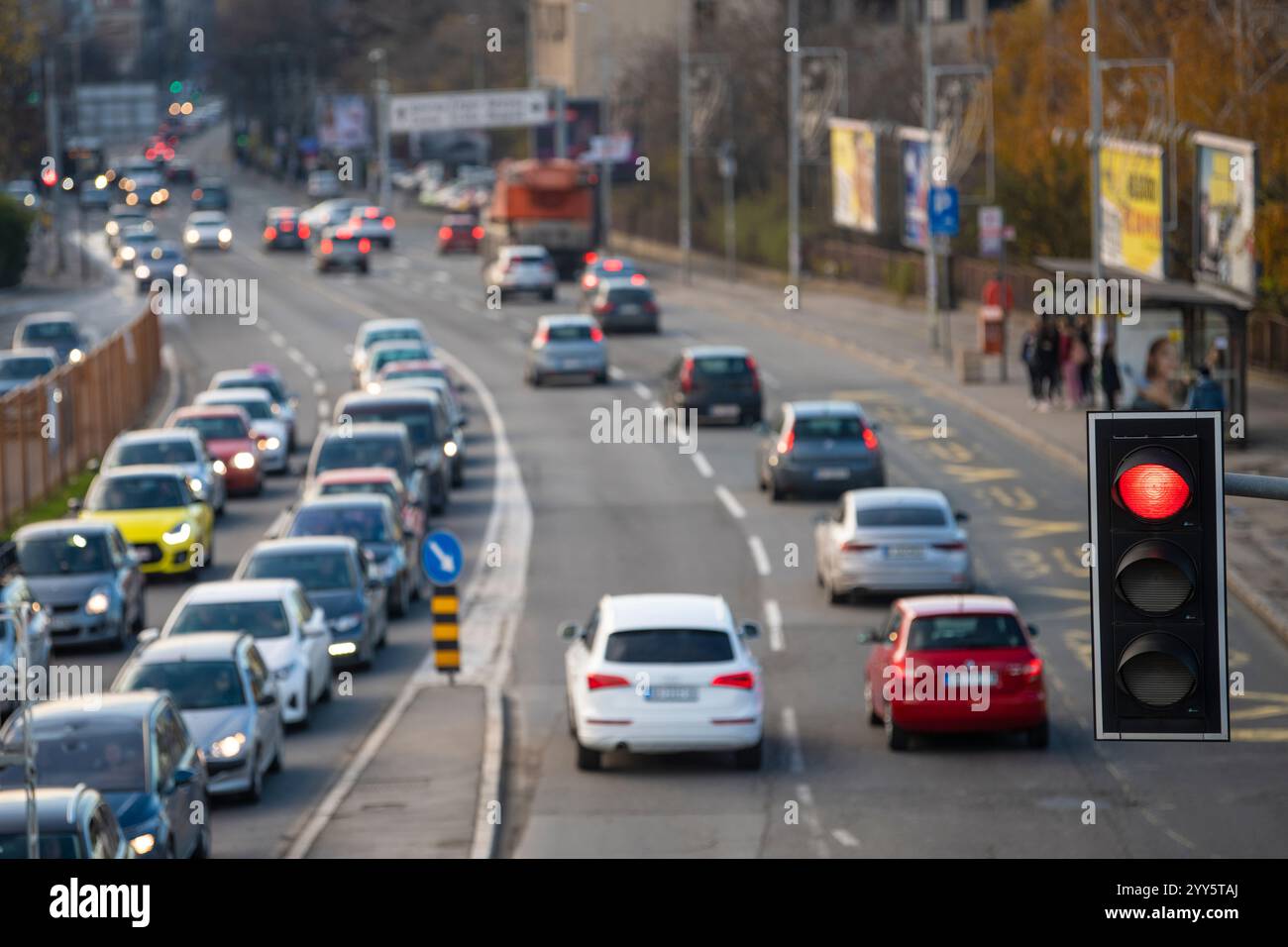 Semaforo o semaforo con un semaforo rosso in primo piano, con vista sfocata del traffico cittadino sullo sfondo. Concetto di regolazione e controllo del traffico. Foto Stock