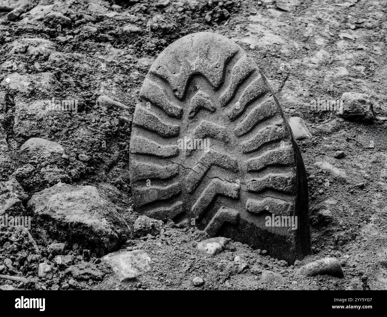 Scoprire il passato. Stivale militare sepolto in tempo . Esplorando la storia e l'archeologia della guerra. Scarpa con impronta a terra. Dettagli monocromatici in bianco e nero. Foto Stock