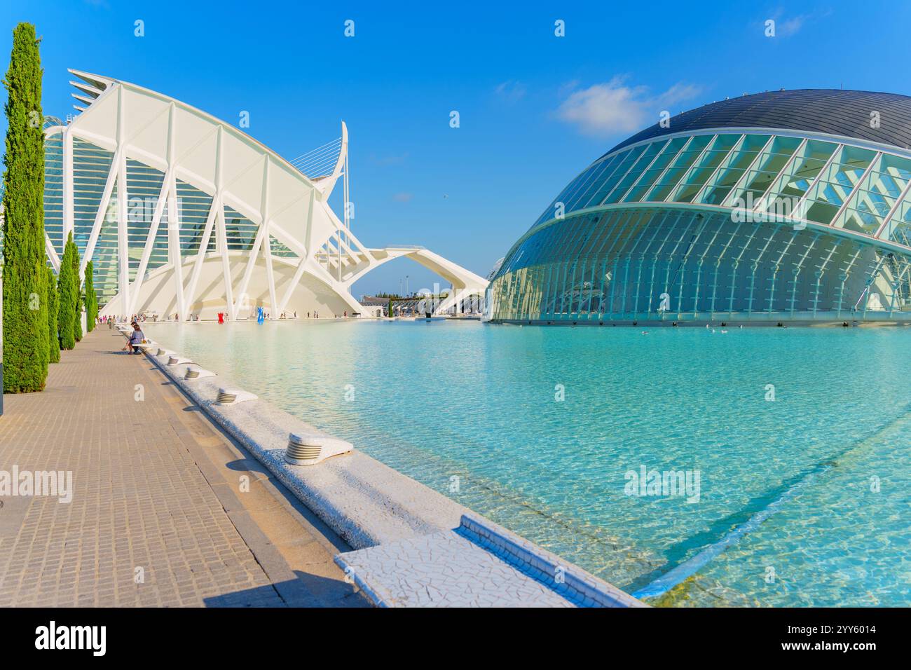 Valencia, Spagna - 12 luglio 2024: Vista della suggestiva architettura moderna di Valencia lungo un tranquillo corso d'acqua, incorniciato da lussureggianti alberi verdi e da un meraviglioso b Foto Stock