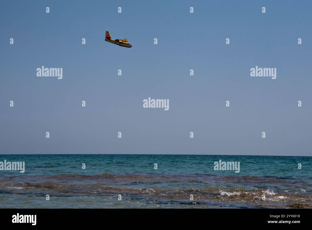 Canadair, Fire-Fighter Airplane, un bombardiere ad acqua bimotore che si prepara a prendere l'acqua dal mare vicino alla spiaggia piena di persone e a scaricarla su un incendio boschivo. Foto Stock