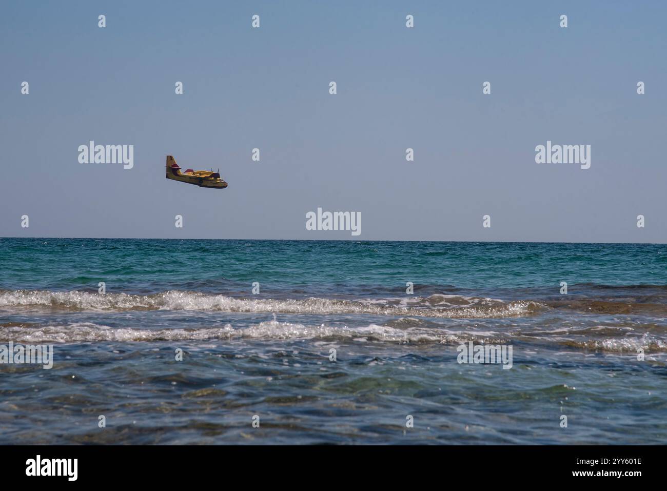 Canadair, Fire-Fighter Airplane, un bombardiere ad acqua bimotore che si prepara a prendere l'acqua dal mare vicino alla spiaggia piena di persone e a scaricarla su un incendio boschivo. Foto Stock
