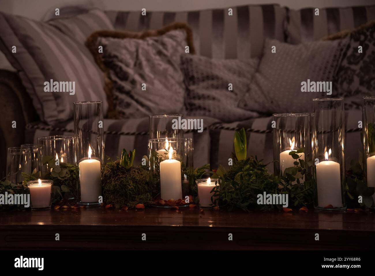 Vasetti di vetro con candele accese illuminano la camera, creando un'atmosfera romantica e calda nella camera da letto retrò con un bel decor sullo sfondo. Foto Stock