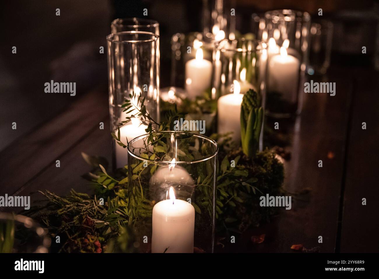 Vasetti di vetro con candele accese illuminano la camera, creando un'atmosfera romantica e calda nella camera da letto retrò con un bel decor sullo sfondo. Foto Stock
