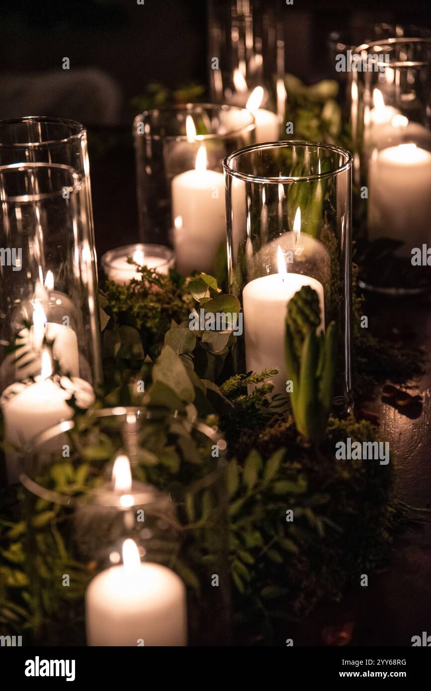 Vasetti di vetro con candele accese illuminano la camera, creando un'atmosfera romantica e calda nella camera da letto retrò con un bel decor sullo sfondo. Foto Stock