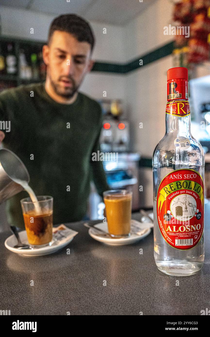 Alosno, Spagna, 14 dicembre 2024, scena di un barista che serve caffè e liquore con una bottiglia di liquore ad Alosno. Foto Stock