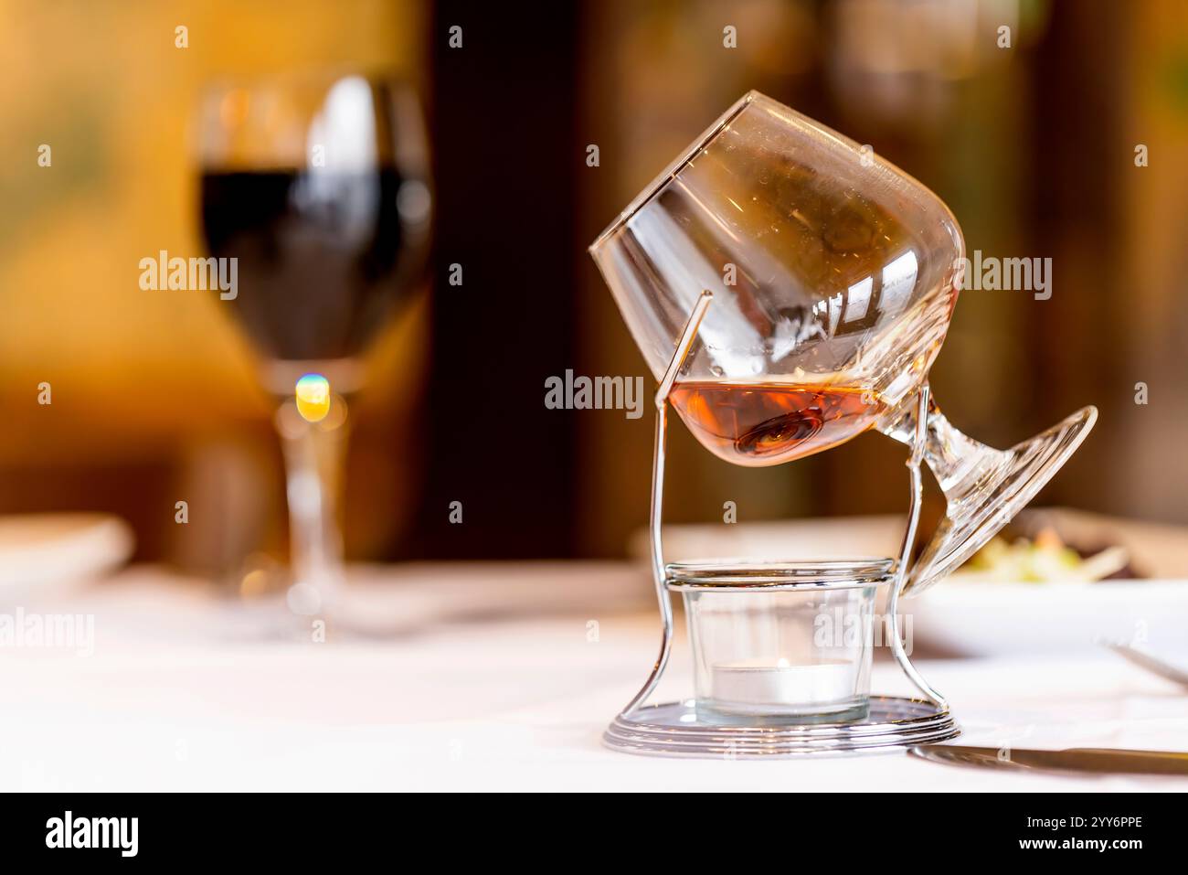 Un brandy riscaldato in un calice di vetro splendidamente esposto su una candela da tè. Foto Stock