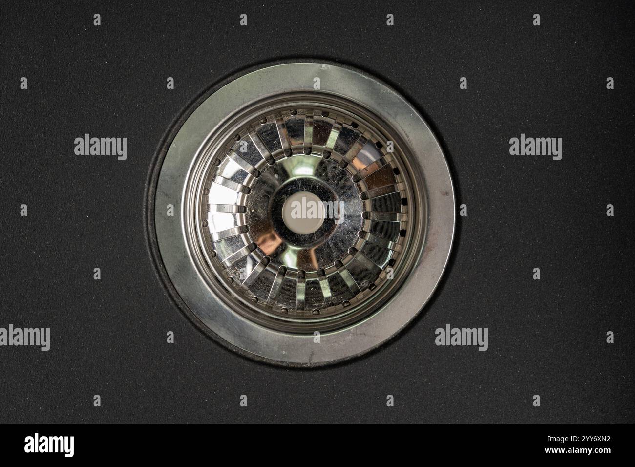 Un'elegante griglia di drenaggio in acciaio inossidabile all'interno di un moderno lavello grigio in pietra artificiale, che mette in risalto il design contemporaneo e la funzionalità della cucina. Foto Stock