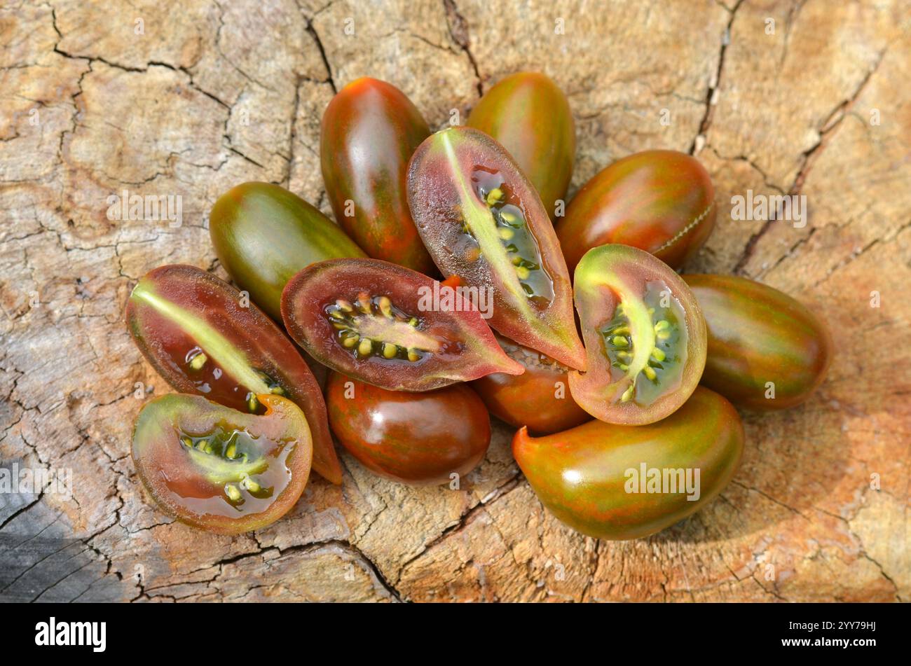 Pomodori maturi a strisce verdi-rosse con punta appuntita, appartenenti alla categoria dei pomodori dell'uva. Concetto di coltivazione di varietà insolite di pomodori. Foto Stock