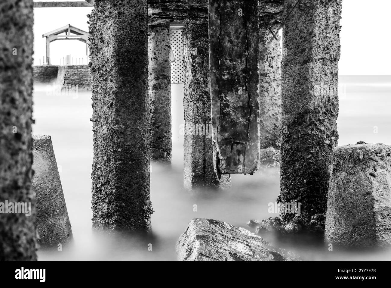 Spettacolare vista in bianco e nero del mare sotto un ponte. Pittoresca vista costiera con acque blu cristalline. Foto Stock