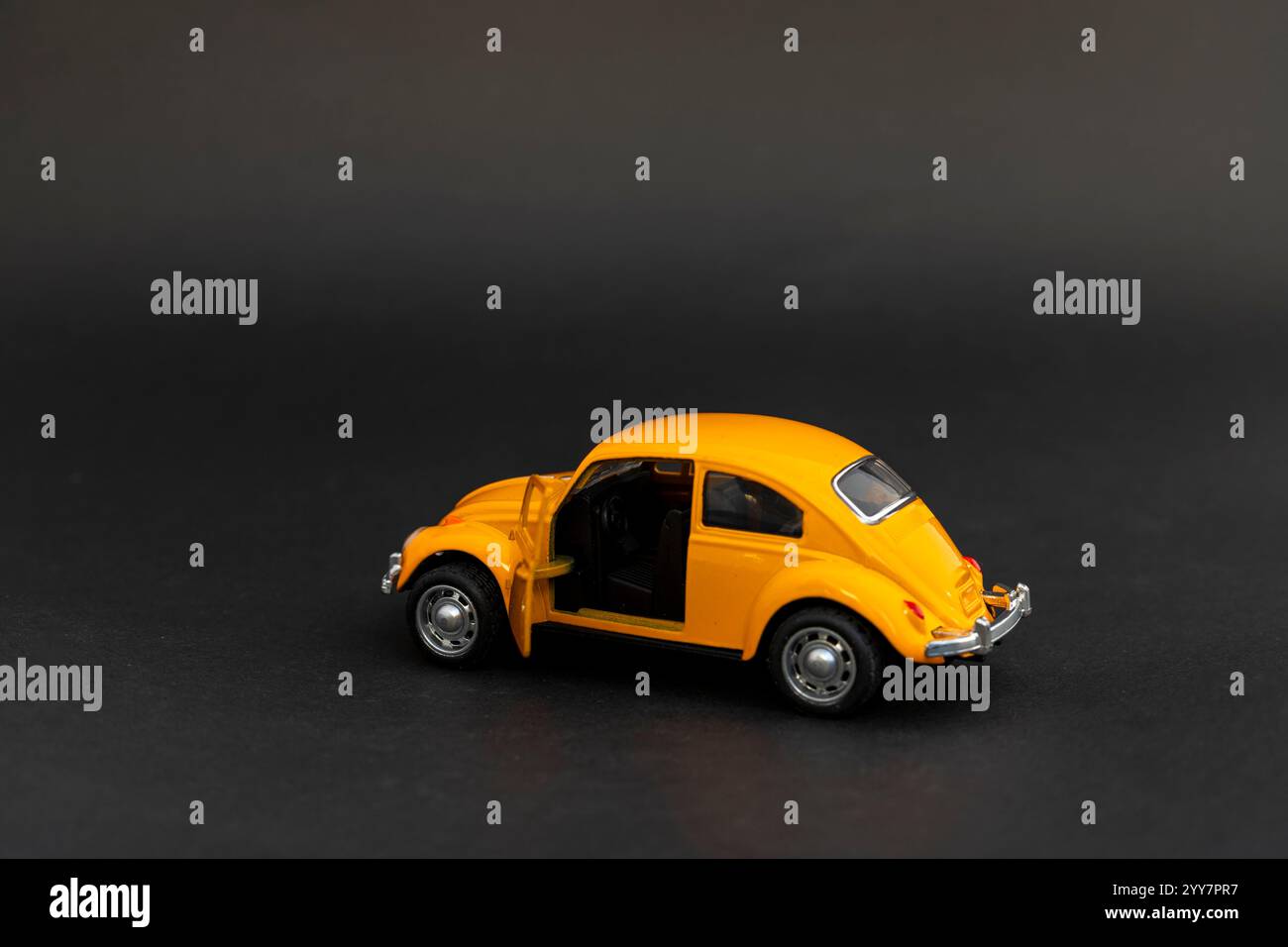 Modello di auto giocattolo in metallo giallo con sportello aperto su sfondo nero Foto Stock