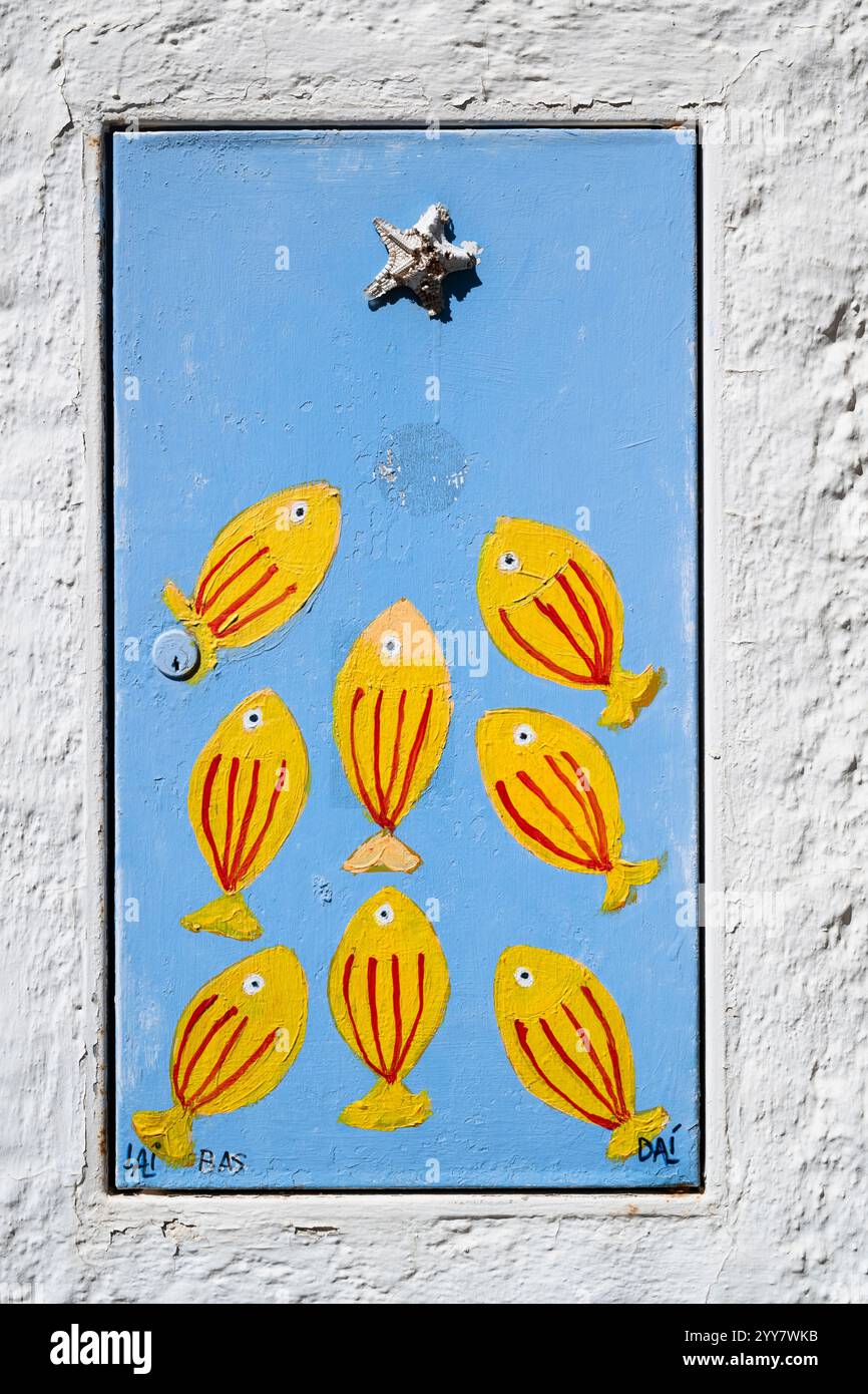 Street art - immagine con il pesce su una porta di una scatola di distribuzione dell'alimentazione nelle strade di Cadaqués, Catalogna, Spagna Foto Stock