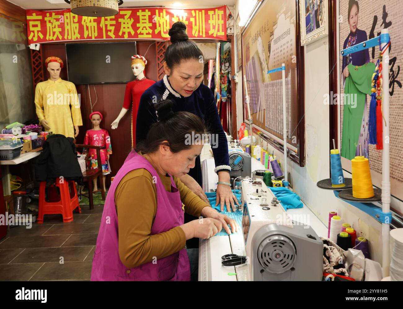 (241220) -- DONGXING, 20 dicembre 2024 (Xinhua) -- fan Wenying (posteriore), patrimonio culturale immateriale erede delle abilità di fabbricazione di costumi Jing, parla con un dipendente a Dongxing, nella regione autonoma Guangxi Zhuang della Cina meridionale, 16 dicembre 2024. Il gruppo etnico Jing è l'unico gruppo etnico marittimo in Cina, la maggior parte dei suoi membri vive sulle tre isole al largo della costa di Dongxing, nelle regioni di confine del Guangxi confinanti con il Vietnam. Essendo uno dei gruppi minoritari più piccoli della Cina, i Jing attualmente contano meno di 30.000. In passato, il popolo Jing si basava completamente sulla pesca tradizionale per guadagnarsi da vivere. B Foto Stock