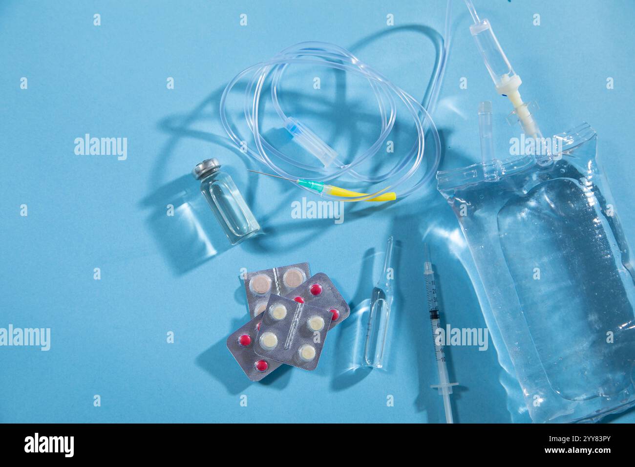 Sacca per infusione, siringa, fiale mediche su sfondo blu. Camera di gocciolamento IV Foto Stock