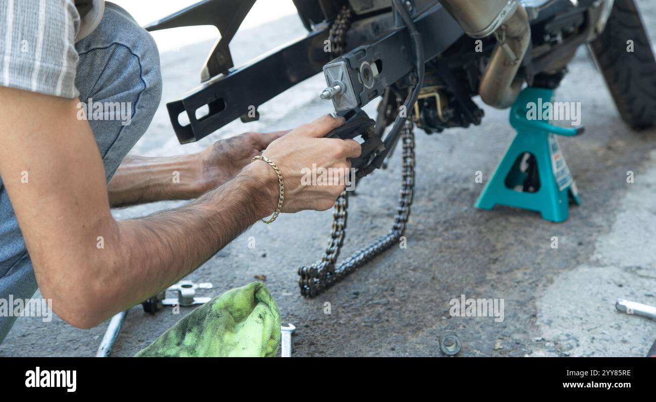 Uomo che ripara catene motociclistiche. Sport. Hobby Foto Stock