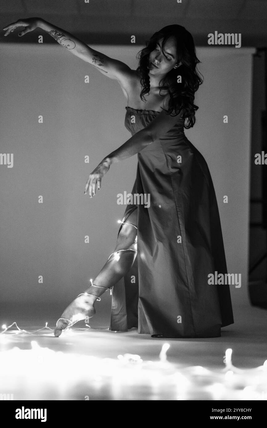 La donna in abito posa elegantemente con luci in bianco e nero Foto Stock