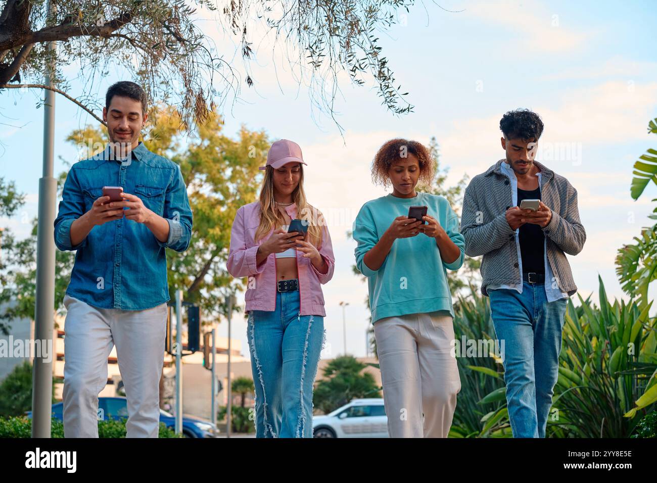 Amici che camminano e utilizzano smartphone durante una giornata di sole nel parco Foto Stock