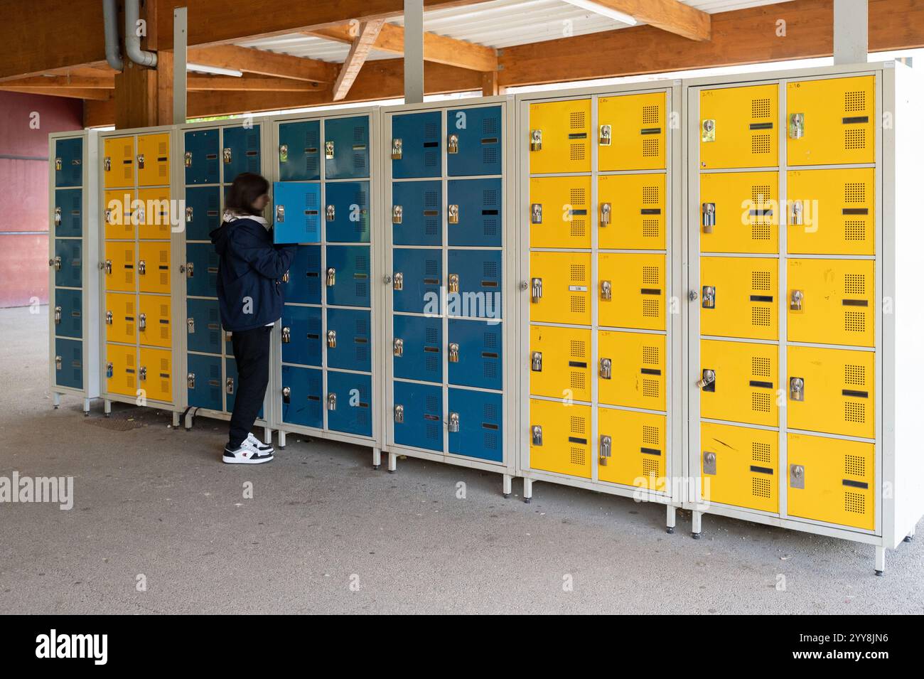 Strutture in una scuola media: Installazione di mobili con armadietti per scolari. Scolaro che mette la sua borsa nel suo armadietto *** locale Foto Stock