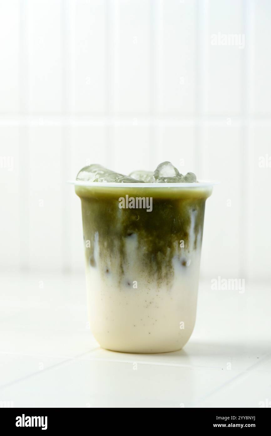 Latte freddo Matcha in vetro monouso in plastica con tè verde Matcha sul latte o latte vegetale Foto Stock