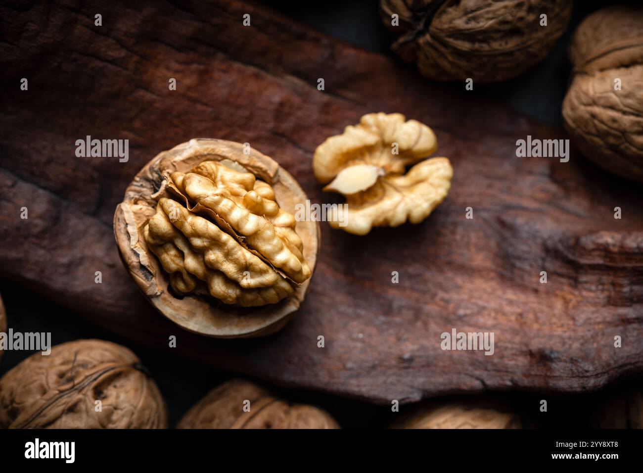 Noce incrinato con semi su una vecchia tavola di legno da vicino. Fotografia gastronomica Foto Stock