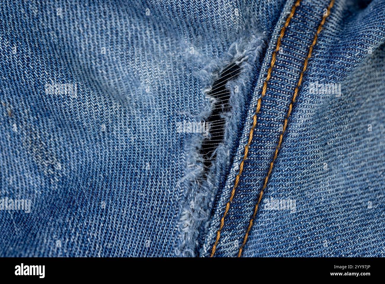 vecchi jeans strappati da usura frequente, jeans danneggiati con un foro nel tessuto adatto per la riparazione e le cuciture Foto Stock