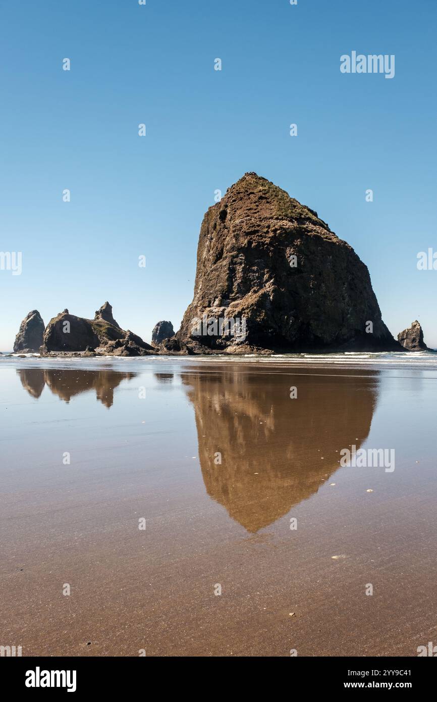 Roccia di fieno riflesso nell'acqua lungo la spiaggia dell'Oregon Foto Stock