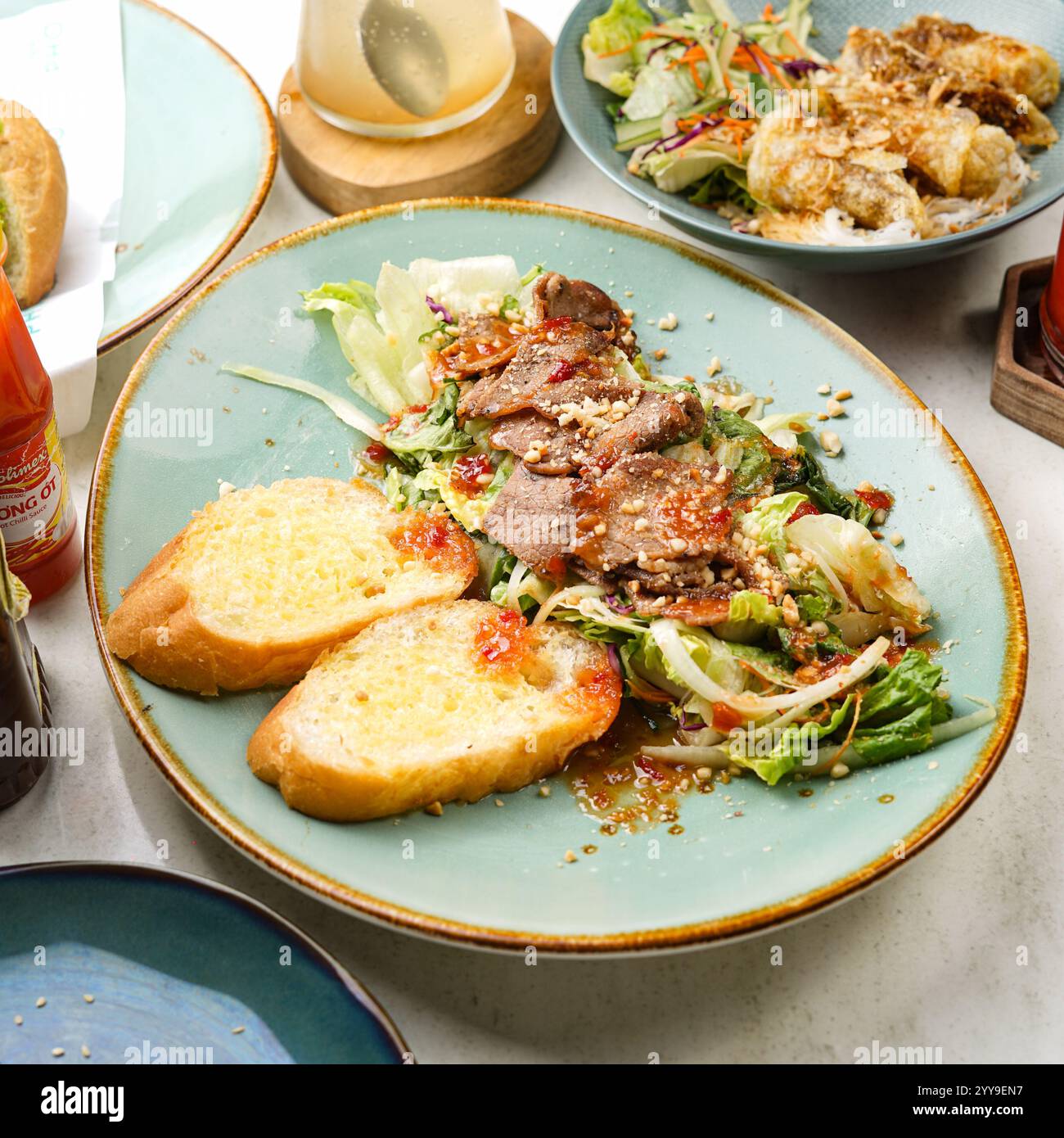 Salata insalata di manzo grigliata condita con arachidi tritate e salsa al peperoncino dolce, servita con pane tostato per una perfetta fusione. Foto Stock