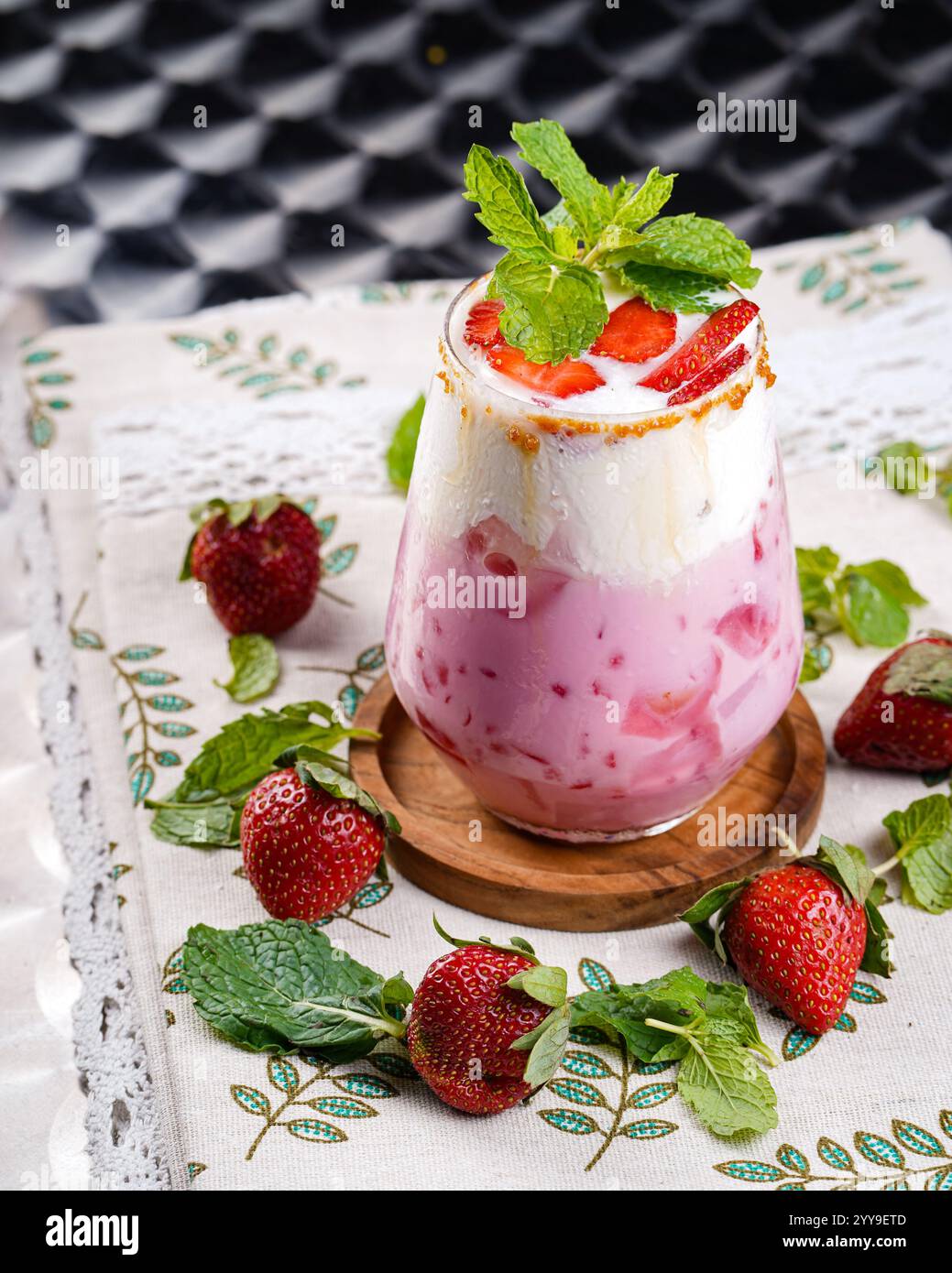 Una bevanda rinfrescante alla fragola e alla panna, splendidamente guarnita con foglie di menta fresche e zucchero caramellato, creando il perfetto equilibrio tra dolciumi Foto Stock