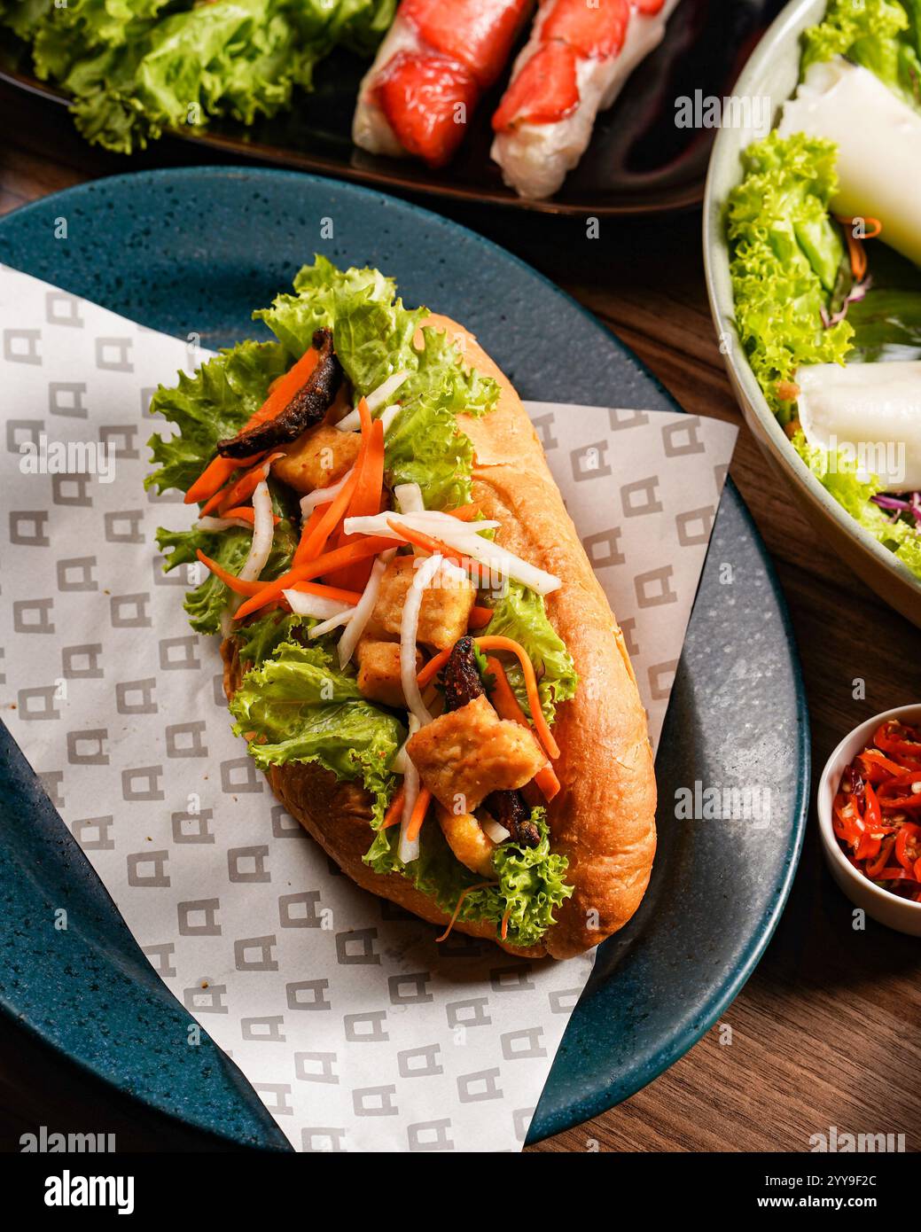 Un fresco e vibrante panino vietnamita bánh mì ripieno di verdure croccanti, erbe aromatiche e ripieno saporito, abbinato perfettamente a un rinfrescante frutto rosso Foto Stock