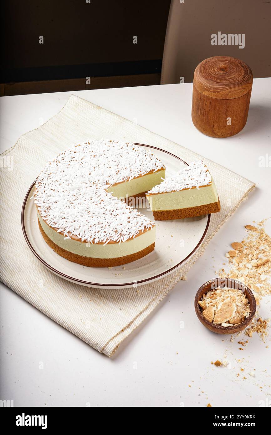 Fette di cheesecake assortite disposte in cerchio su un piatto bianco, con una varietà di sapori e condimenti tra cui cioccolato, frutta e cocco Foto Stock